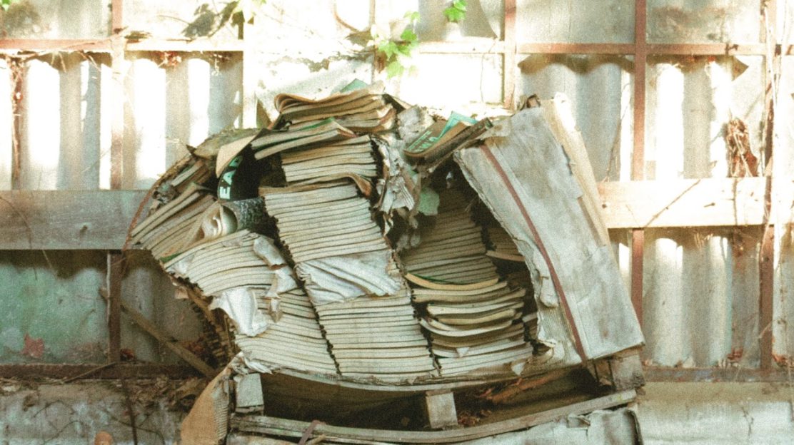 Stack of weathered old ledgers and documents in a dilapidated storage building